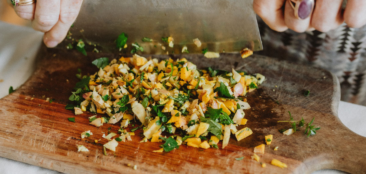 Hands chopping herbs with a large knife